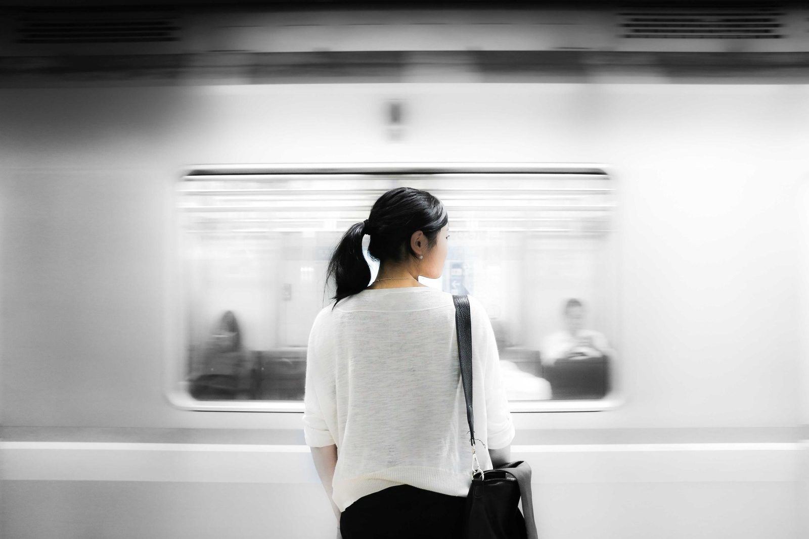 Une passante immobile devant une rame de métro en mouvement